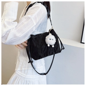 Chic black pleated bucket bag with cute white plush charm on model side view