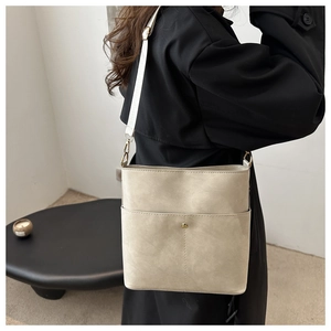 Detail view of cream textured leather bucket bag with gold magnetic buckle on model