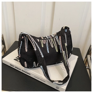 Detail of black hobo bag featuring colorful embroidery on textured pleated fabric