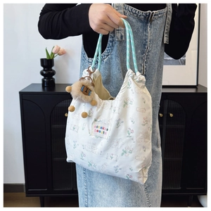 Detail of floral tote bag with rabbit print, rope handle, and plush lion charm