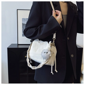 Detail of white textured bucket bag with woven handle and plush charm on black blazer