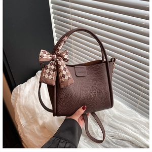 Detail der dunkelbraunen Eimer-Tasche mit Seidenschal und Fashion-Prägung aus Leder