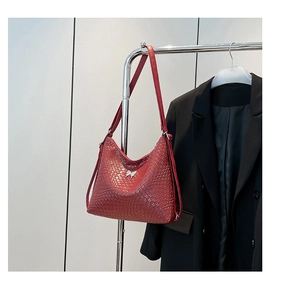 Detail of red woven leather shoulder bag featuring a silver butterfly buckle decoration