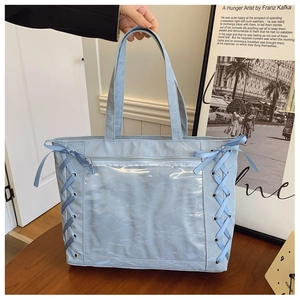 Close-up of light blue ita bag with transparent PVC window and side ribbon lace-up detail