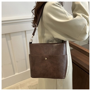 Detail of dark brown leather bucket bag with retro texture and gold buckle on shoulder strap
