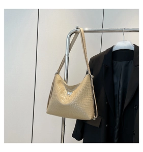 Detail of beige shoulder bag with crocodile texture and silver butterfly buckle