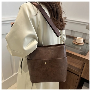 Detail of vintage coffee brown bucket bag with gold buckle and wide fabric strap