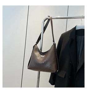 Detail of coffee brown crocodile pattern shoulder bag with silver bow hardware and leather strap