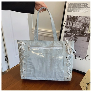 Close-up of light blue tote bag featuring silver eyelets and satin ribbon side details