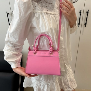 Chic pink handbag for women featuring gold hardware and a stylish woven knot detail