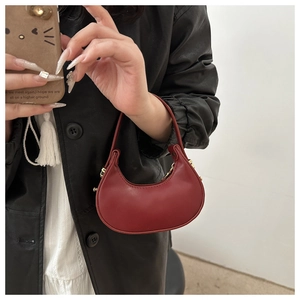 Gros plan d'un sac demi-lune rouge en cuir minimaliste avec une texture lisse et des boucles