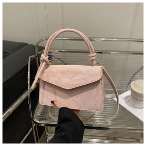Detail van lichtroze handtas met V-vormige flap en geplooide synthetische textuur