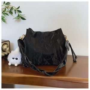 Close-up of black pleated cloud bag texture with gold hardware and white plush charm