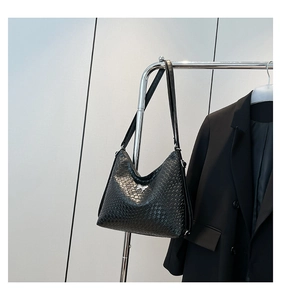 Detail of black woven leather shoulder bag featuring a silver horse-shaped metal hardware