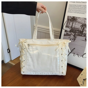 Detail of white tote bag featuring clear PVC window and ribbon bow cross-lacing design
