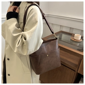 Detail of deep brown PU leather bucket bag with wide strap and metallic stud detail