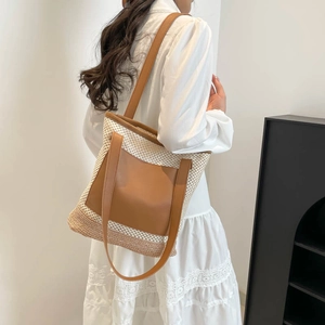 Large straw woven tote bag with brown leather straps shown on a female model for vacation