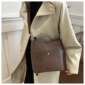Close-up of vintage brown bucket bag featuring fine leather texture and wide strap