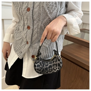 Détail du sac croissant avec imprimé léopard gris et finitions métalliques dorées