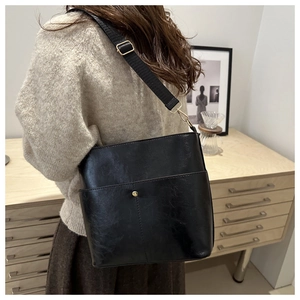 Black vintage bucket bag shown from a side perspective on a model with metallic hardware
