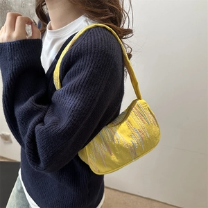 Yellow baguette bag with colorful embroidery texture worn by a model in a casual outfit