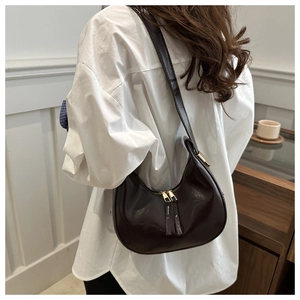 Detail of glossy chocolate brown crescent underarm bag with adjustable leather strap