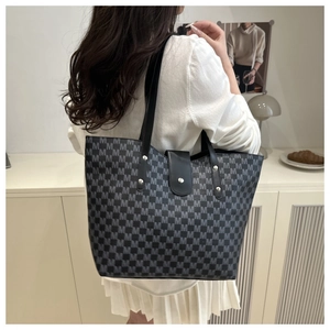 Close-up of a large grey tote bag featuring M-letter jacquard and black leather straps