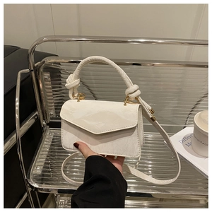 Detail van witte mini-tas met textuur, het unieke geknoopte handvat en de envelopsluiting
