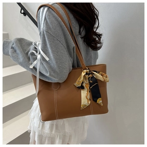 Detail of brown PU leather tote with white contrast stitching and a silk scarf handle