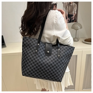 Detail of a large tote bag with M-letter jacquard pattern and leather shoulder straps