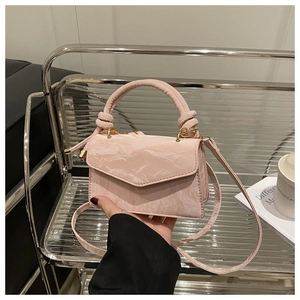 Detail van roze mini-handtas met getextureerd leer en goudkleurig knoop-handvat