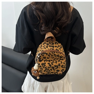 Detailed back view of a corduroy leopard print mini backpack with a plush monkey charm