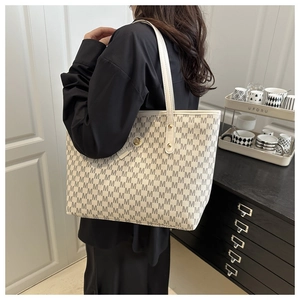 Detailed side view of off-white tote bag with grey M pattern and gold metal logo