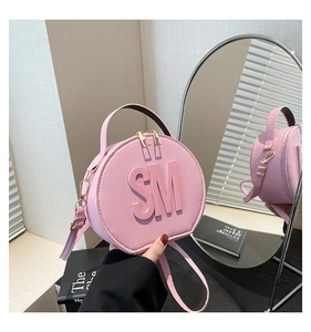 Pink round leather handbag featuring SM embossed letters and golden zip detail