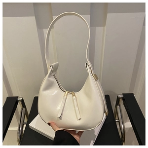 Close-up of white crescent moon bag with dual gold zippers and smooth leather finish