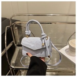 Detail van lichtblauwe mini-handtas met gedraaid handvat en gouden magneetsluiting