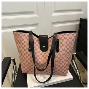 Detail of light pink tote bag with M letter print and black straps on a chair