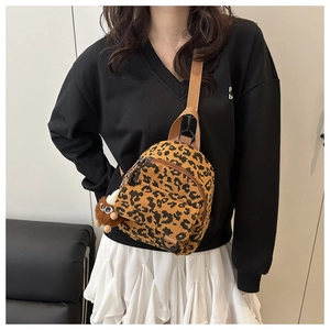 Close-up of leopard print corduroy mini backpack with furry pom-pom charm on model
