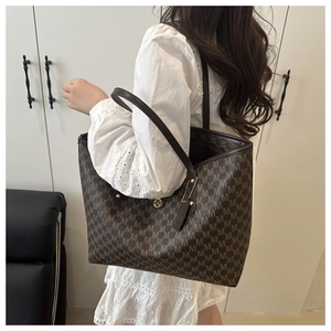 Shoulder view of a large brown tote bag with all-over M monogram and gold logo detail