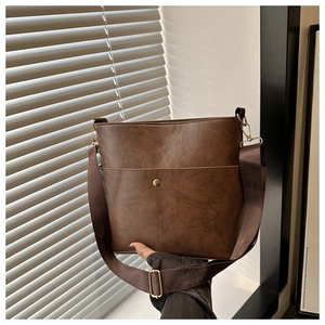 Detail view of brown vintage bucket bag featuring gold buckle and wide fabric shoulder strap