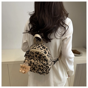 Detailed back view of a mini leopard print corduroy backpack with a cute bear charm