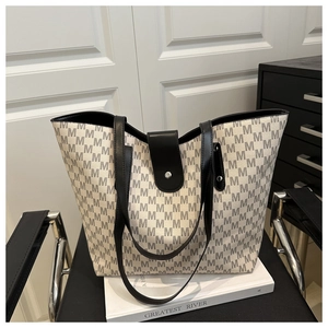 Detail of grey monogram canvas tote with black leather straps and magnetic silver closure