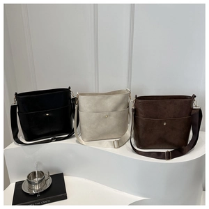 Chic bucket bags in black, beige, and brown colors displayed on elegant white steps