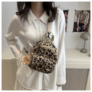 Detail of leopard print corduroy mini backpack with plush pendant on a crossbody strap