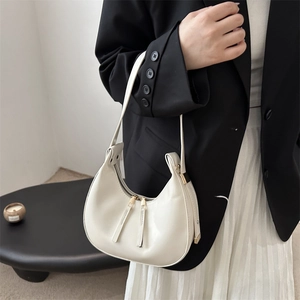 Minimalist white leather hobo crescent bag with dual zippers shown on a stylish model