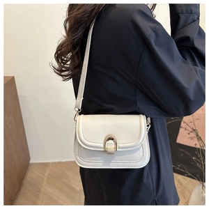 Side view of model wearing a chic white saddle bag with golden metallic buckle