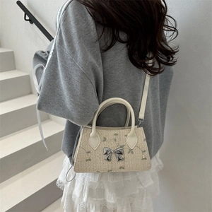 Beige woven straw crossbody bag with floral embroidery and silver metal bow buckle