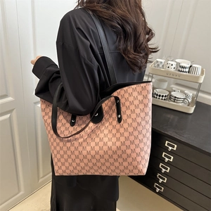 Pink tote bag with all-over M monogram print and black leather straps on a model