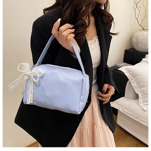 Detail of light blue crossbody bag with large lace bow and elegant white pearls