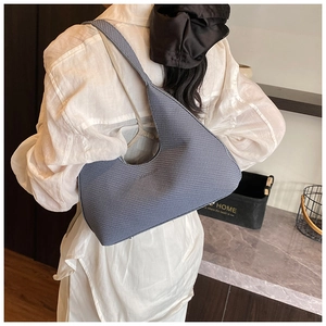 Gros plan du sac croissant bleu brume avec texture quadrillée et logo embossé